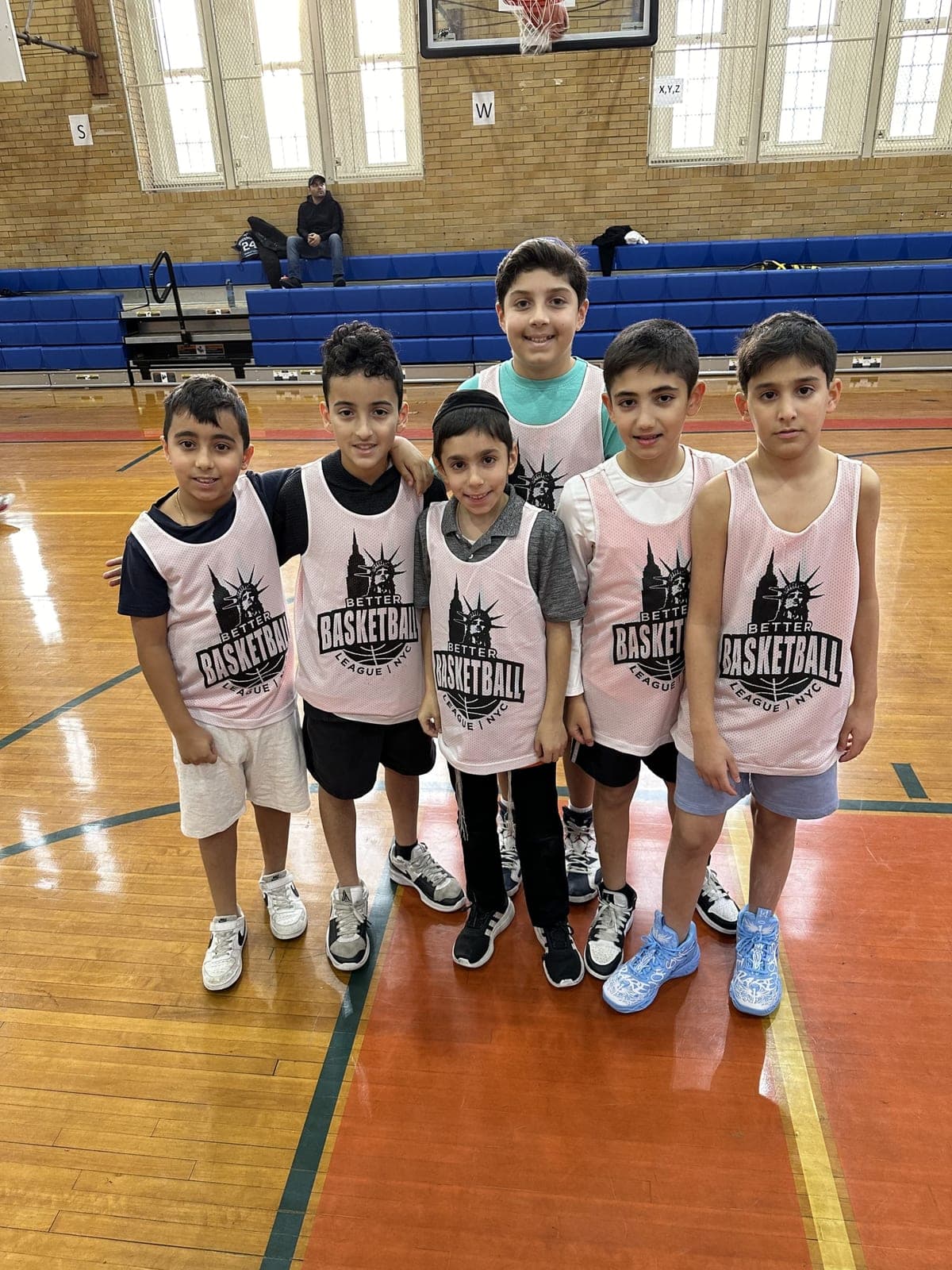 A group of players in pink BBL NYC pinnies standing shoulder to shoulder on the court