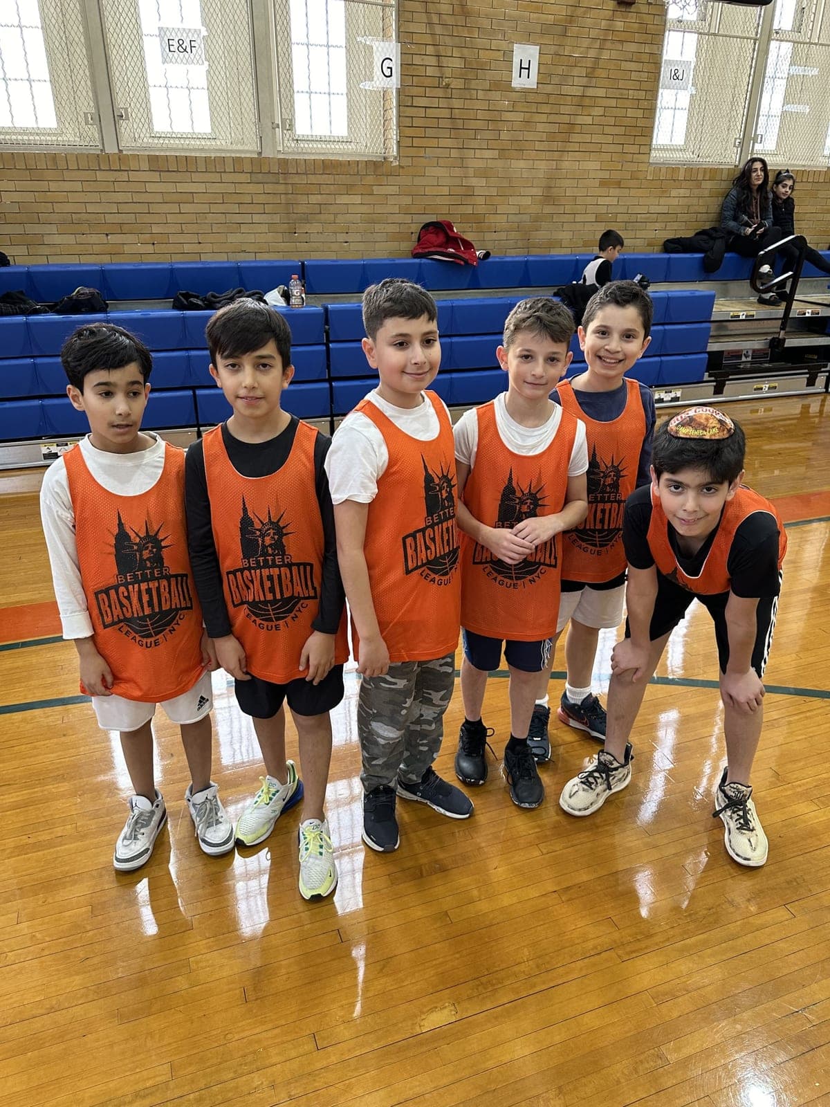 Players in orange pinnies gathered in front of the folded bleachers