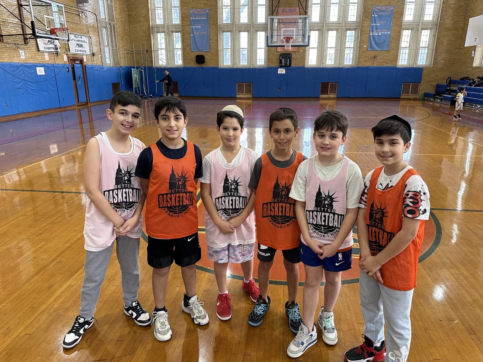 Six players in orange and pink pinnies lined up at mid-court