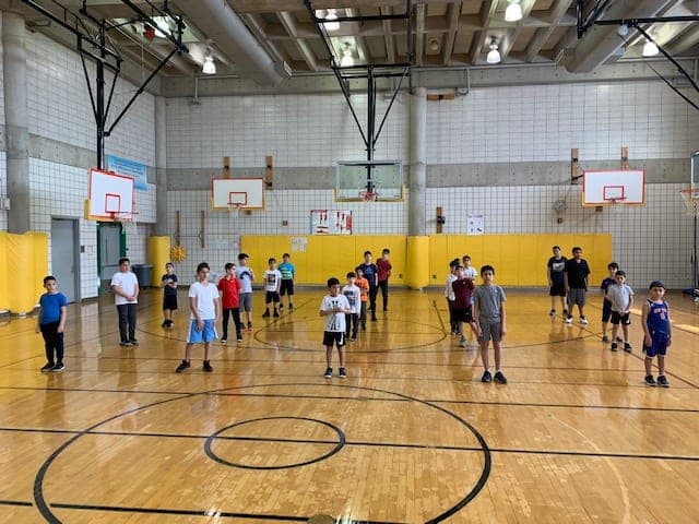 Players spread out across the gym in rows, each on his own spot at the start of a session