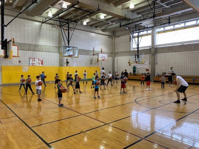 A gym full of players dribbling basketballs during a spread-out warm-up drill