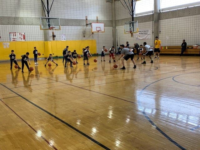 Players working ball-handling drills in a line down the length of the court